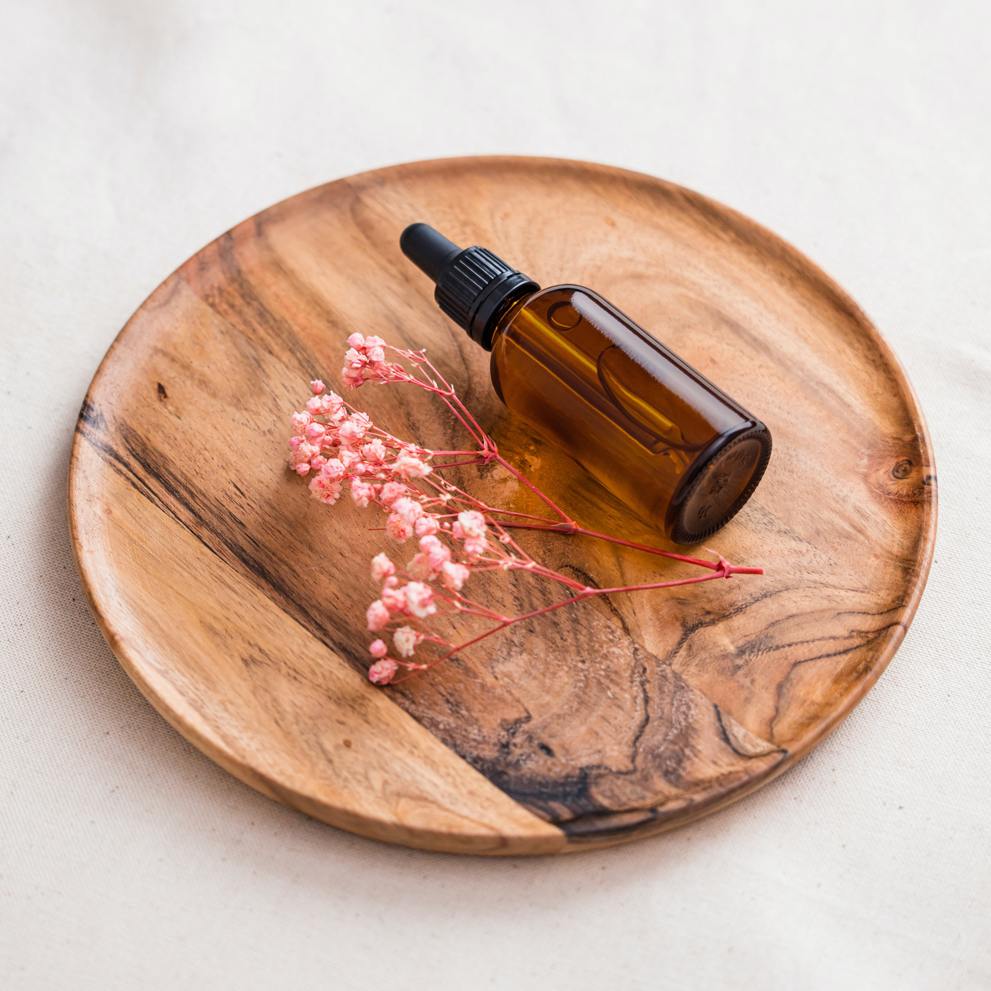 Brown bottle and pink flowers on a wooden surface.