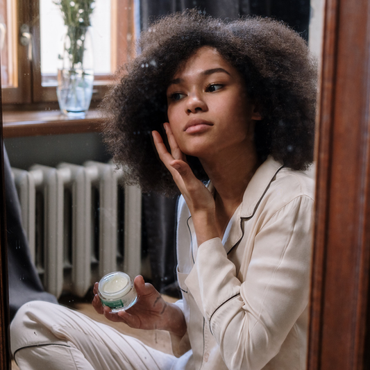 Woman looking at herself in the mirror and putting on a cream