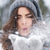 young woman enjoying the sensation of cold weather on her skin while playfully blowing snow from her gloved hands